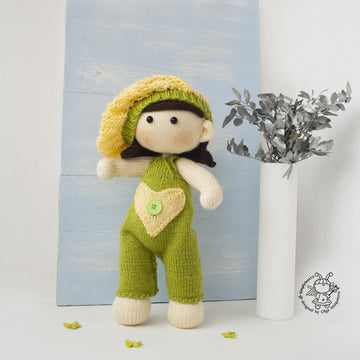 Baby doll in green overalls knitting flat