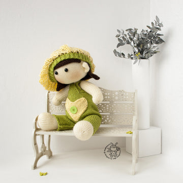 Baby doll in green overalls knitting flat